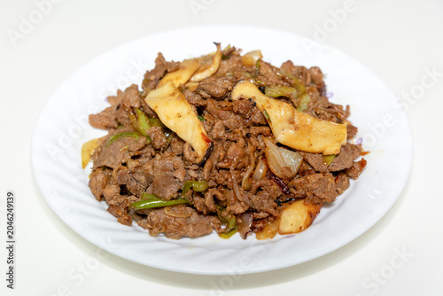 Korean beef bulgogi stir fried with mushrooms, onions, and green onions, featuring savory soy sauce seasoning and authentic Korean cuisine on a white plate.