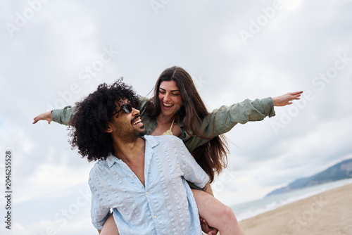 Quadro su tela Smiling couple enjoying piggyback ride on beach