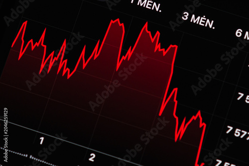 Close-up of a red stock market chart showing a downward trend on a digital screen. Financial graph decline with a sharp red drop line on a dark interface, macro shot.