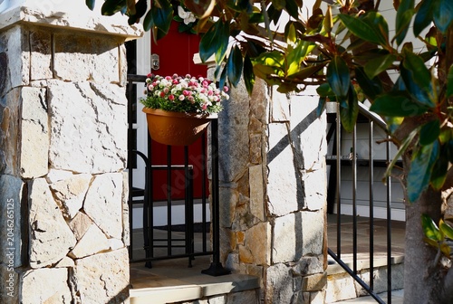 Tableau sur toile Colorful potted plant hangs between stone porch pillars