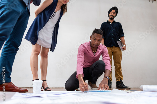 Canvas Print Diverse team collaborating on a project, one person writing on paper