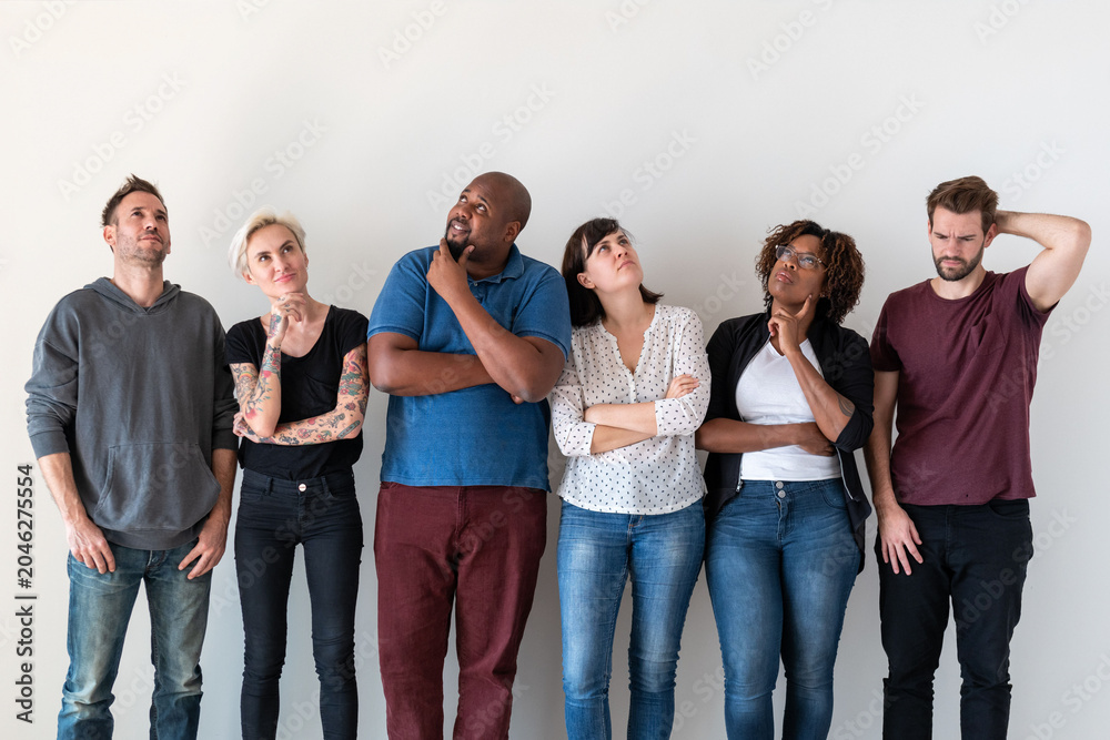 Obraz premium Diverse group of people standing thoughtfully against a white wall.