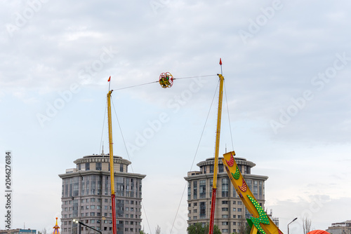 Fotografi A thrilling reverse bungee ride (slingshot) catapulting passengers high into the sky against the backdrop of modern residential skyscrapers in a city amusement park, Bishkek, Kyrgyzstan