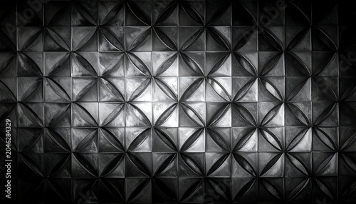 A black and white image of a wall with a repeating pattern of raised, three-dimensional triangles