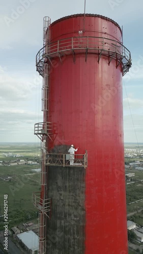 Industrial alpinism,industrial climbing Painters Coating Tall Chimney Stack at Industrial Facility Maintenance and Restoration Work at Height.Professional industrial painters performing maintenance