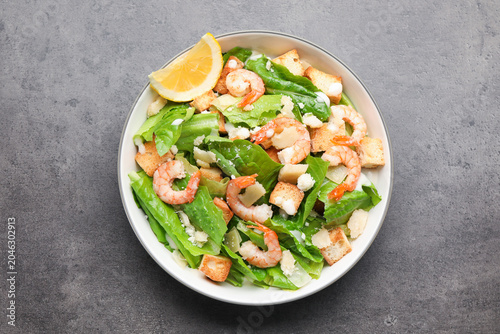 Schilderij op canvas Delicious Caesar salad with shrimps in bowl on grey table, top view