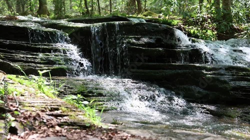 Water cascades over a stepped waterfall in a forest scene