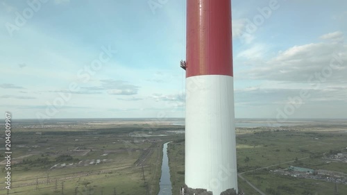 Industrial alpinism,industrial climbing Painters Coating Tall Chimney Stack at Industrial Facility Maintenance and Restoration Work at Height.Professional industrial painters performing maintenance