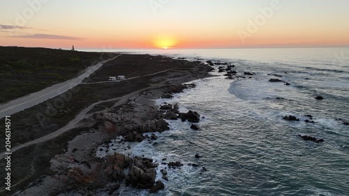 Sunset Over Rocky South Africa Coastline, Aerial Drone Sweep Reveals Winding Coastal Road, Scattered Boulders,
