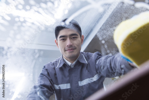 Photos Car wash worker scrubbing windshield with sponge through soapy glass