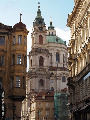 Narrow streets of the historic Prague Old Town with the magnificent St. Nicholas Church rising in the background. Architecture and cultural heritage of Prague, Czech Republic. 04.04.2026