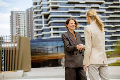 Foto Meeting between two businesswomen in a city outside office buildings