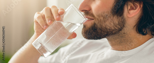 Bild auf Leinwand Focused Man With Beard Drinking Water From Glass, Sitting Comfortably At Home Sh
