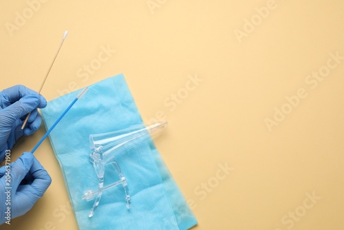Foto Doctor with sterile gynecological examination kit on beige background, top view