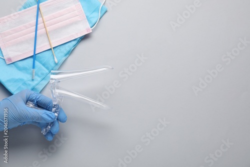 Bild auf Leinwand Doctor with sterile gynecological examination kit and medical mask on light background, top view
