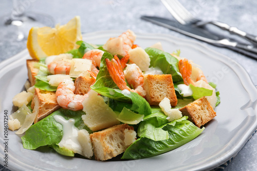 Schilderij op canvas Delicious Caesar salad with shrimps served on grey table, closeup