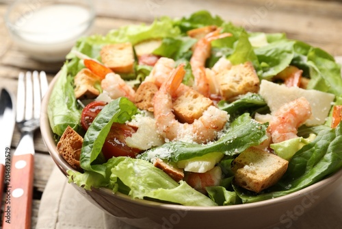 Canvas-taulu Delicious Caesar salad with shrimps in bowl served on table, closeup