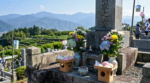 Traditional Obon festival offerings arranged on stone gravestones in a mountain cemetery. Obon festival decorations include fresh flowers, incense, and sweets placed carefully at ancestral graves.