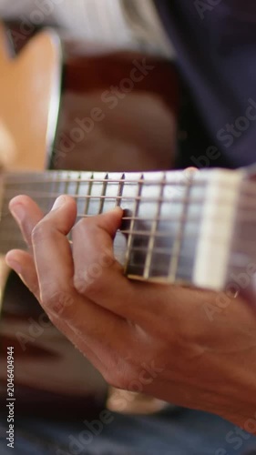 Vertical video: Closeup showing player left hand pressing frets on guitar while practicing at home