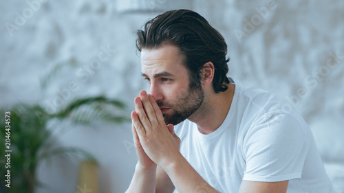 Photos Worried Expression On Face Of White Male Adult Sitting On Couch With Hands Toget