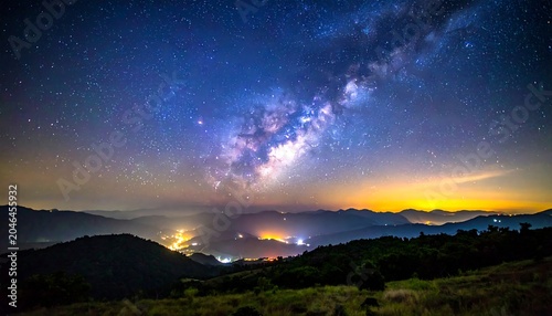 A breathtaking panoramic view of the starry night sky with the Milky Way visible above a mountainous landscape at dusk