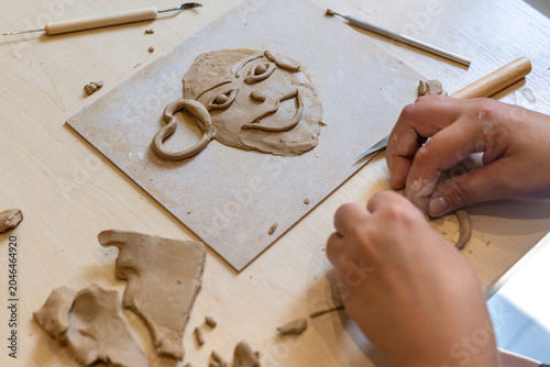 Canvastavla close-up of a person's hands sculpting an expressive clay face portrait on a wor