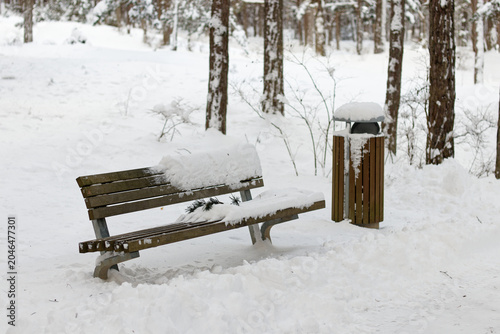 City park bench partially cleared of snow in winter