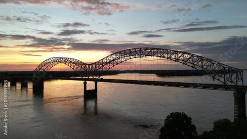 Aerial view of a large steel arch bridge over a river at sunset