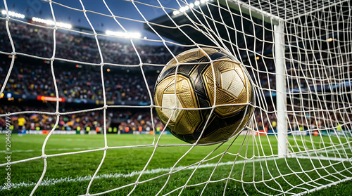 Soccer ball flying into goal net during a stadium match at night