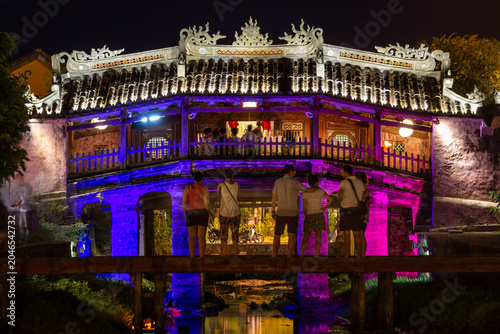 Tableau sur toile Tourists looking at the historic Japanese Covered Bridge illuminated by vibrant