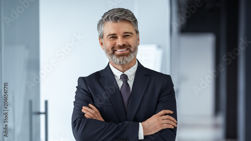 Tableau sur toile Confident Middle Aged Caucasian Man Smiling With Arms Crossed While Standing In Modern Office Setting, Projecting Professionalism And Success
