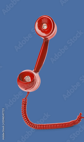 Konstfotografi Red telephone handset with cord on blue background