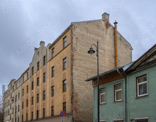 Apartment Building with Expressive Yellow Facade Next to Older Wooden House in Riga, Latvia