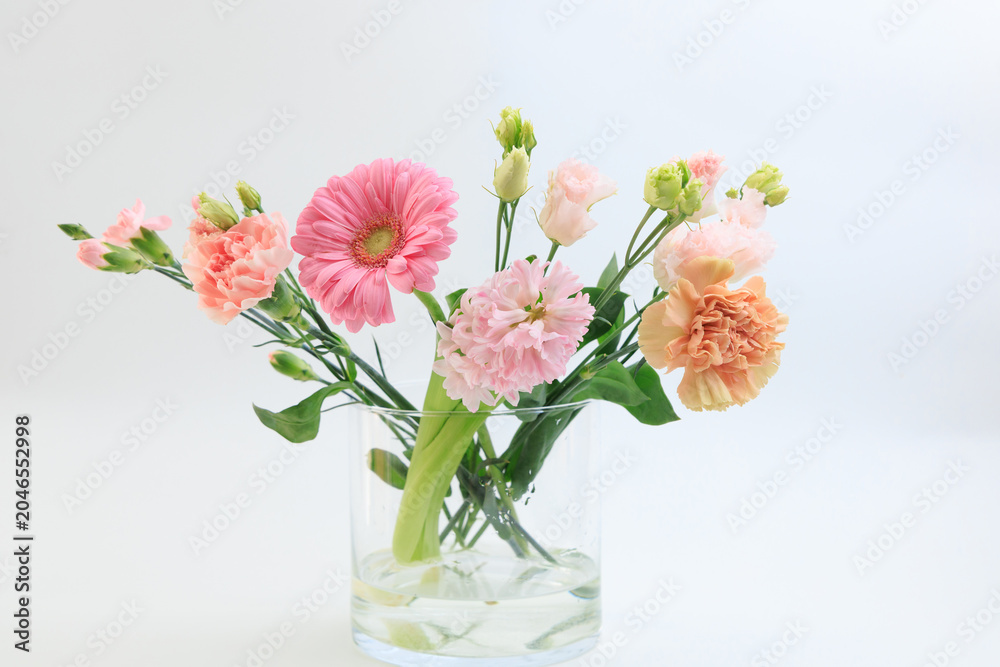 Obraz premium Bouquet of gerbera and carnations arranged in a glass vase on a simple background for decoration