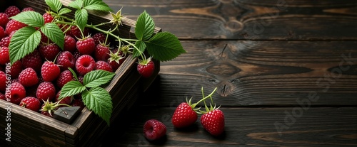 Fresh raspberries spill from a wooden crate. Berries gleam with dew on dark wood. Green leaves add freshness to rustic scene. Perfect for food blogs