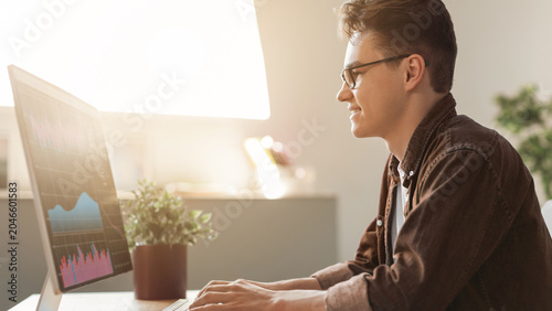 Fotografija Focused Young Caucasian Man Using Computer While Working At Home Office, Engaged