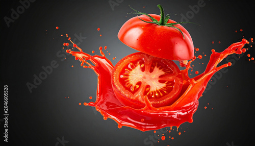 A vibrant tomato splashing into its own juice, creating a dynamic explosion of red liquid. The tomato is cut in half, revealing its juicy interior