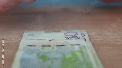 Defocused horizontal 4K video close up. Male hand counts green paper banknote 50 GEL, fifty lari bill, Georgian cash money on wood table. Concept of salary, budget, pay tax, loan, debt, wages, credit