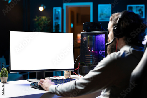 Foto Man using gaming station mockup monitor, excited to finally relax by playing videogame on PC at computer desk late at night