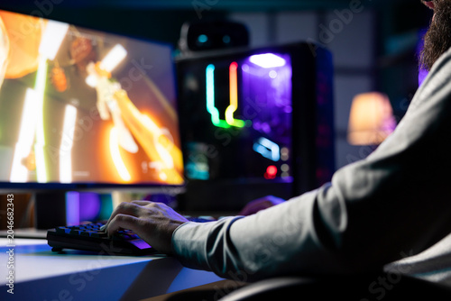 Fotografie Man playing first person shooter videogame with automatic gun shooting laser bullets at flying robotic foes, close up