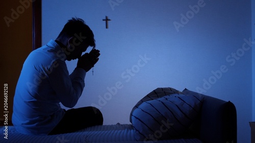 Valokuva Man finding solace and devotion in prayer at night, kneeling on his bed with fol