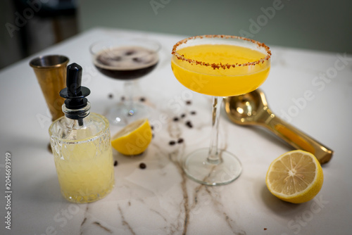 Close up of measured liquor stream entering cocktail shaker with fresh lemon garnish, artisanal Margarita creation and mixology training concept 