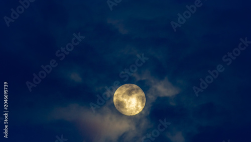 Super full moon in the night sky with clouds,
