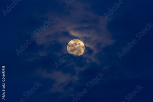 Super full moon in the night sky with clouds,