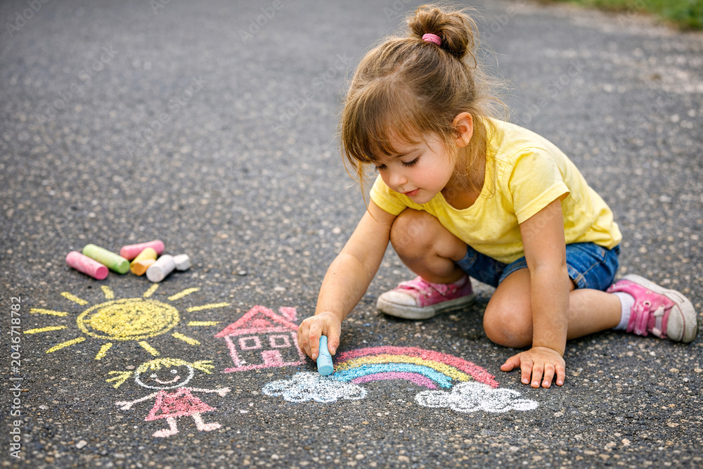 Fototapeta premium Young Girl Drawing Chalk Pictures on Asphalt Road