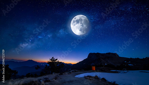 Full moon illuminates a vast canyon landscape at twilight, stars dot the deep blue night sky above, offering a sense of serene wonder and natural beauty