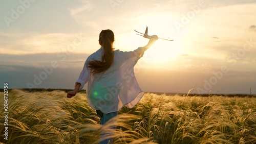 Photos Happy kid girl runs with toy airplane on field in sunset light