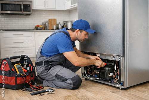Repairman working on refrigerator