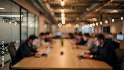 Modern coworking workspace with professionals collaborating at a long conference table in a contemporary office environment
