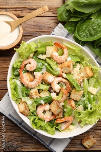 Photos Tasty Caesar salad with shrimps on wooden table, flat lay